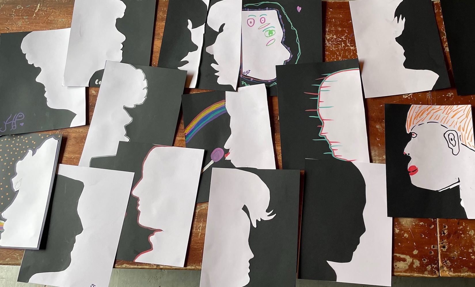 Photograph of students' paper silhouette artworks scattered atop a table